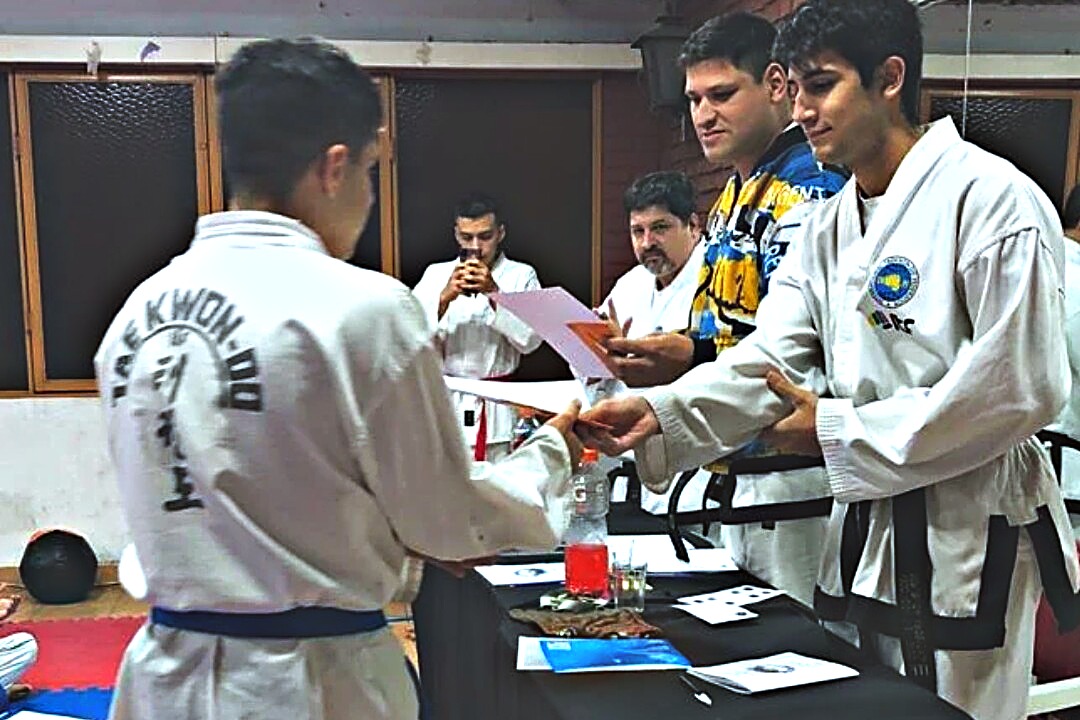 Un alumno recibiendo su hoja frente a la mesa de examen